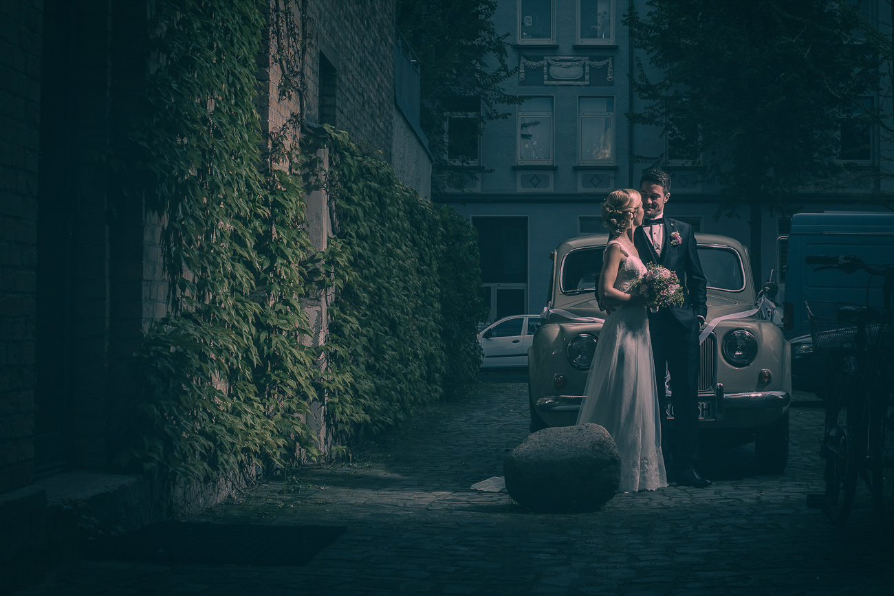 Hochzeitsfoto von Fotoagentur Otto – professioneller Hochzeitsfotograf in Goslar. Romantisches Brautpaar steht in einer historischen Altstadtgasse vor einem Oldtimer. Emotionale, stimmungsvolle Hochzeitsfotografie aus Goslar von Fotoagentur Otto.